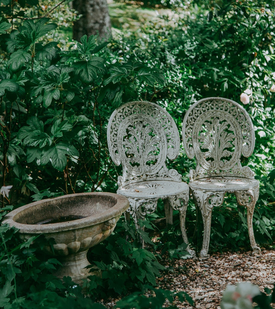 A pair of garden chairs and bird bath.